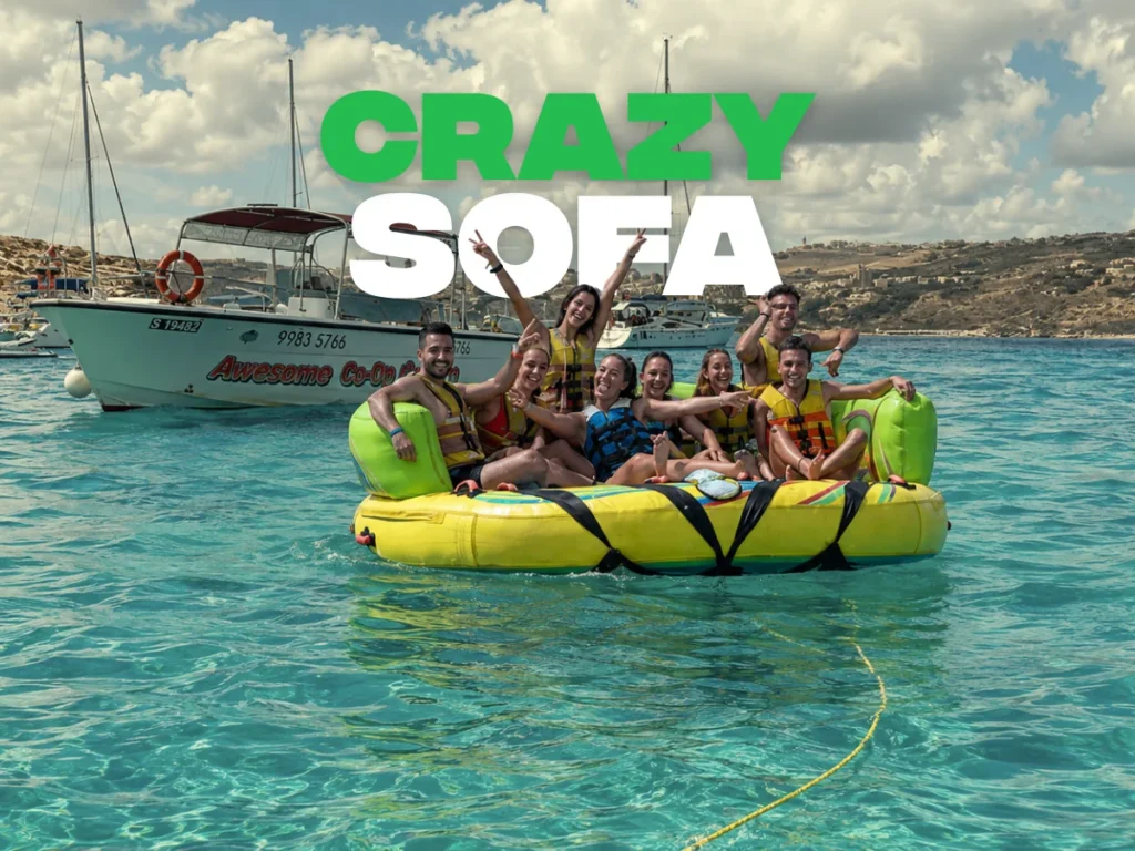 Grupo de jóvenes sobre un sofá hinchable a remolque de una lancha en el mar de Malta
