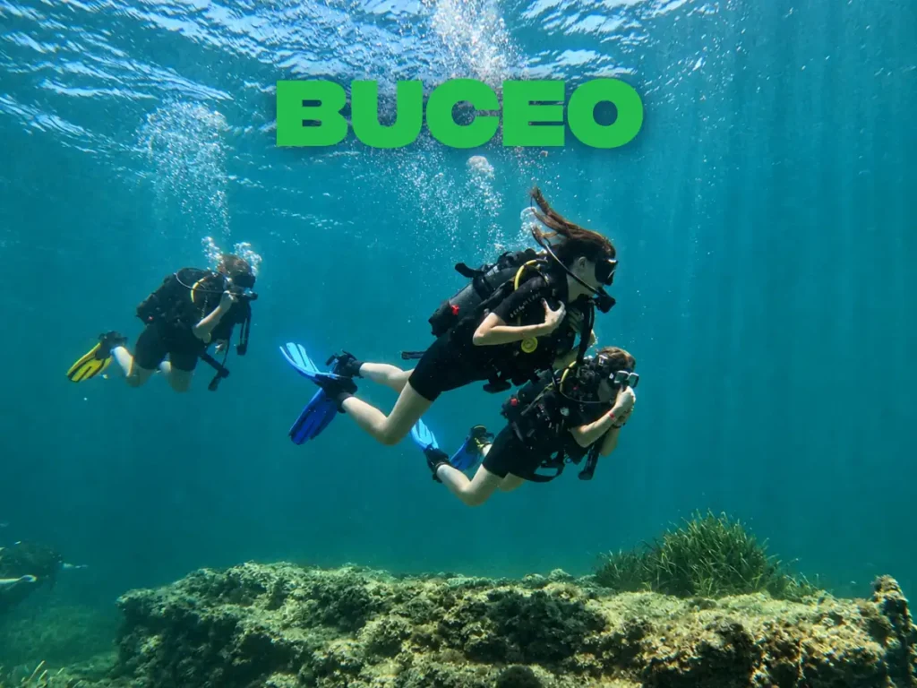 Tres buceadores con equipo de submarinismo nadando sobre el fondo rocoso del Mediterráneo en Malta