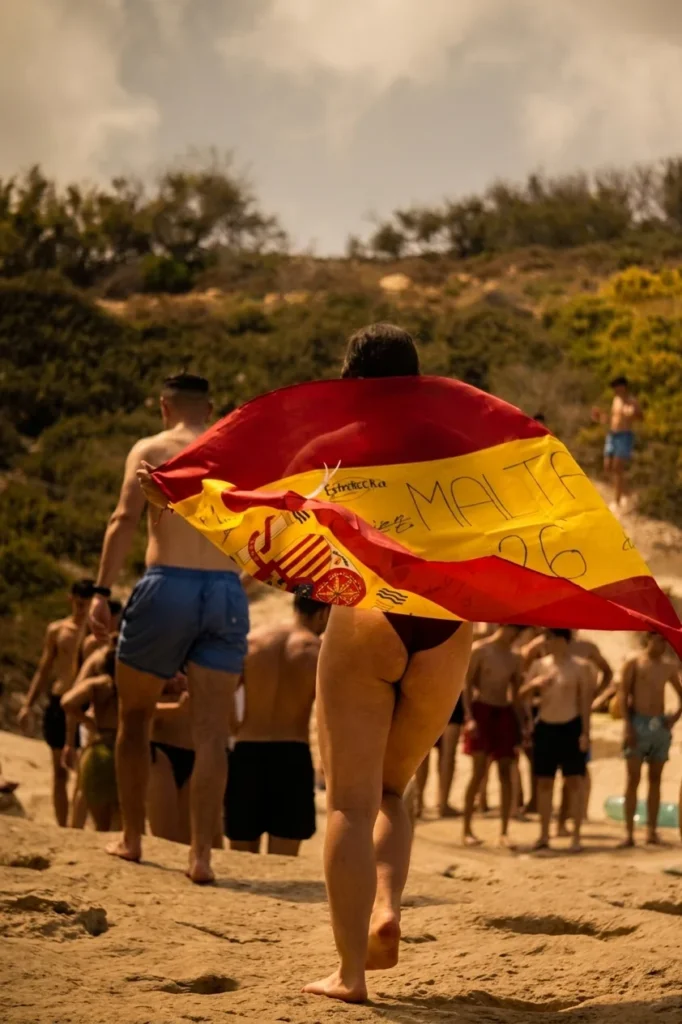 Grupo con la bandera de España en una playa de Malta al atardecer