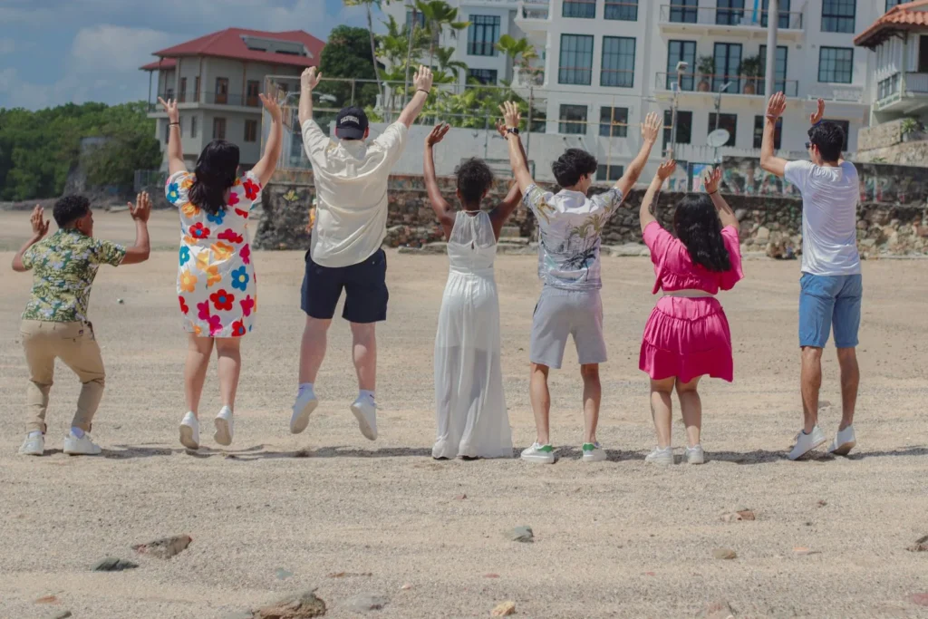 Grupo de amigos saltando juntos en una playa de arena blanca del Caribe