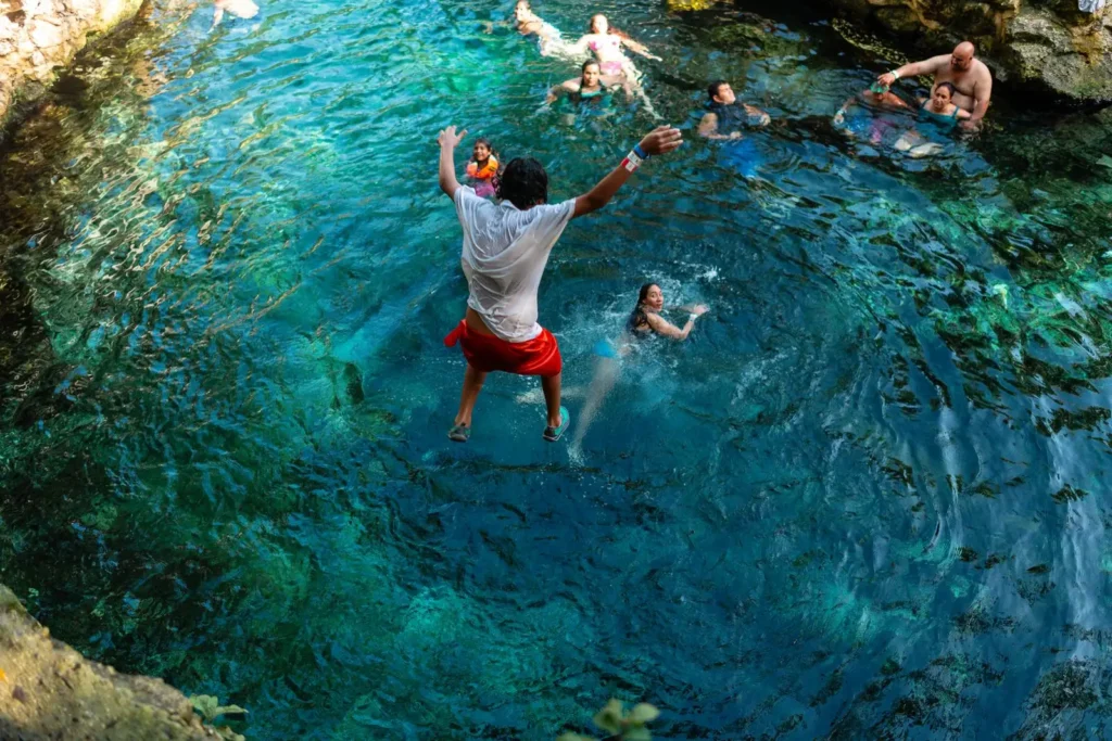 Jóvenes bañándose y saltando al agua de un cenote de la Riviera Maya