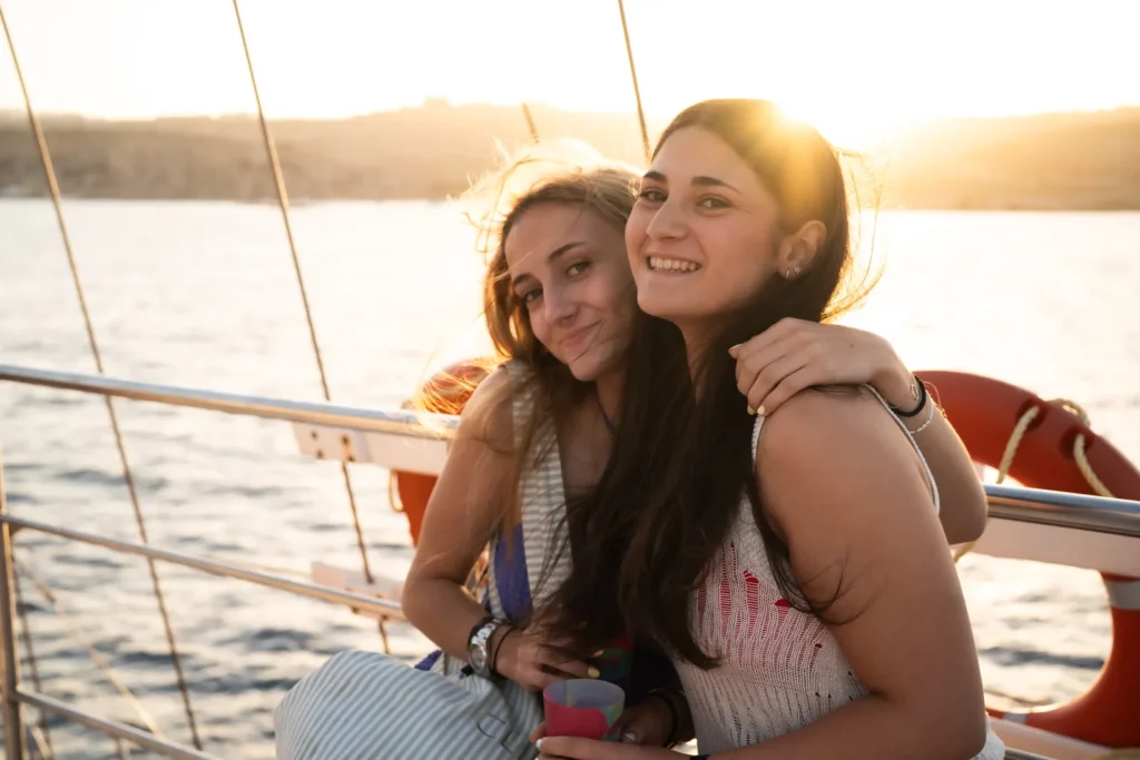 Dos amigas abrazadas al atardecer en el barco durante un viaje en grupo a Malta