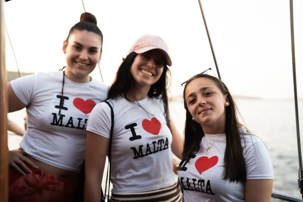 Tres chicas con camisetas I love Malta en el barco durante su viaje de fin de curso