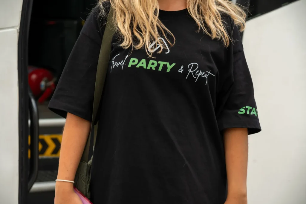 Camiseta del staff de Tu Viaje Agency con el lema Travel, Party & Repeat